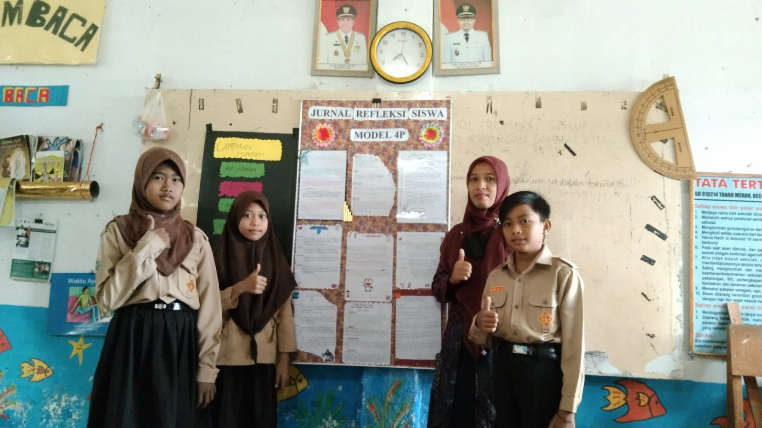 Tati Hariyanti, guru kelas 5 SD Negeri 03 Tanah Merah Kabupaten Batubara bersama siswa-siswinya saat memajang hasil Jurnal Refleksi Siswa di dinding kelas